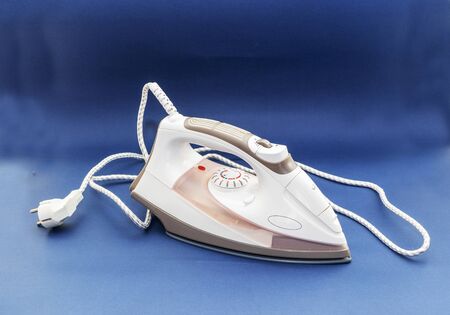 Modern steam electric iron in white on a blue background.の写真素材