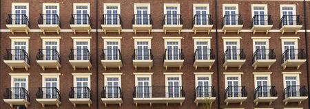 Front view of a modern residential brown brick building with balconies and Windows, close-up,...