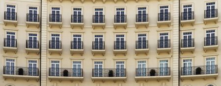 Front view of a modern residential brown brick building with balconies and Windows, close-up,...