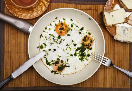 Pan of fried eggs, bacon with bread and tea on dark table surface, top view.の写真素材