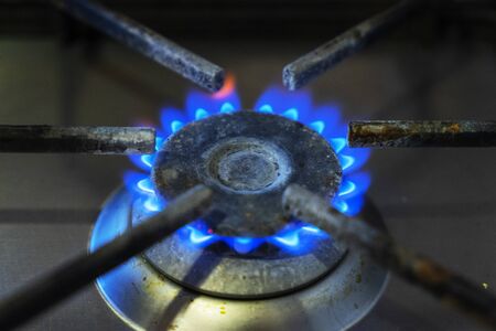 Blue flames of gas burning from a kitchen gas stove. Focus the front edge of the hotplate.の写真素材