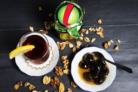 Azerbaijani black tea in a glass of armudu, walnut jam, and walnuts on the table. Azerbaijani, Turkish, Oriental cuisine, tea traditions.の写真素材