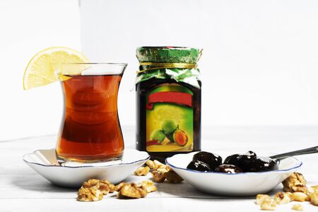 Azerbaijani black tea in a glass of armudu, walnut jam, and walnuts on the table. Azerbaijani, Turkish, Oriental cuisine, tea traditions.の写真素材