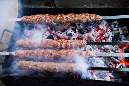 Set of Shish Kebabs or Barbecue Shashlik Collection on Charcoal Background with Herbs and Spices. Skewered Grilled Cubes Mix of Poultry Chicken Meat, Salmon Fish, Beef and Lamb Top Viewの写真素材
