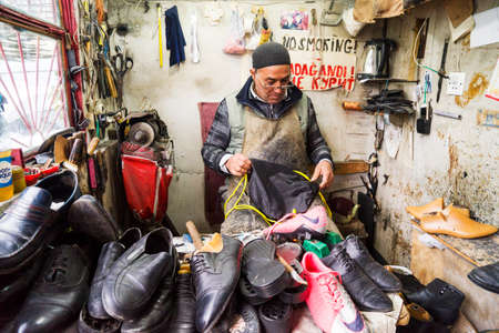 BAKU,AZERBAIJAN- 12 JULY 2019 : a shoe maker working in his workshop.のeditorial素材