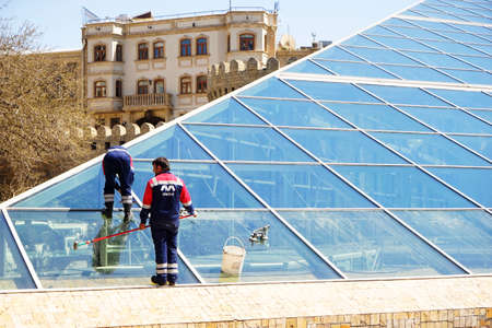 Baku, Azerbaijan- 20 May 2019: Window cleaners washing office windows with ropes.のeditorial素材
