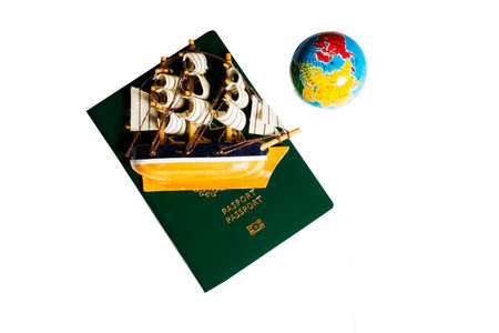 small toy ship on a green passport and globe on white background