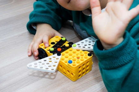 a Little 6 years old boy collects the designer parts. Child designs. Activities of children in...