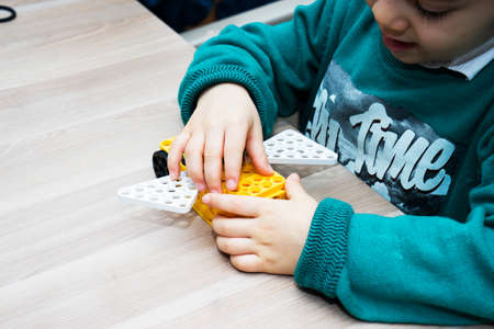 a Little 6 years old boy collects the designer parts. Child designs. Activities of children in...