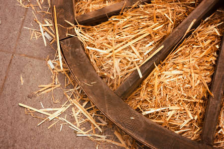 old wooden wagon wheel lies in the mangerの写真素材