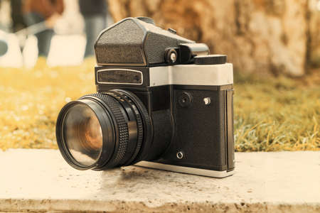 Vintage Soviet film camera on a boulder on a blurry background of nature. Shallow depth of field...