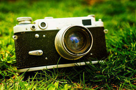 Vintage Soviet film photo camera lying on the grass in nature Shallow depth of field with focus on...