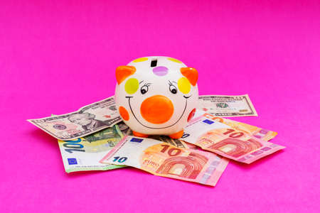 Piggybank with banknote on pink