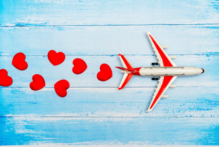Airplane toy and heart on blue wooden background, love travel concept