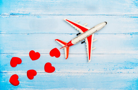 Airplane toy and heart on blue wooden background, love travel conceptの写真素材
