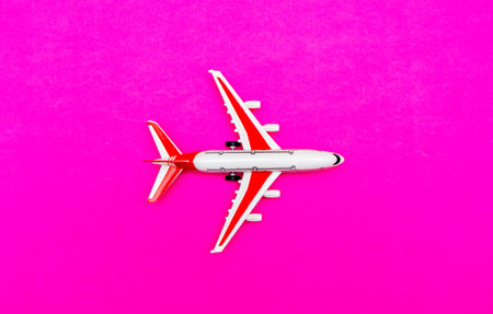 White and red Passenger Model airplane on a red, pink background. Free space for text. Travel...