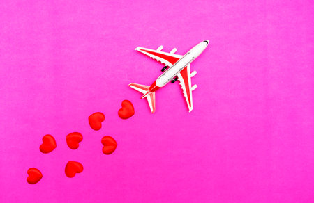 Airplane toy and heart on red, pink background, love travel conceptの写真素材