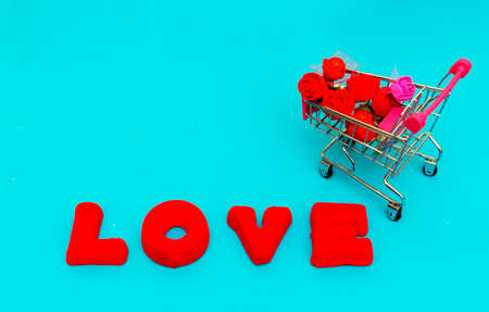 The word Love in red letters and a food cart with flowers on a blue background. Creative Valentine's Day mock up. Love flat lay with word.の写真素材