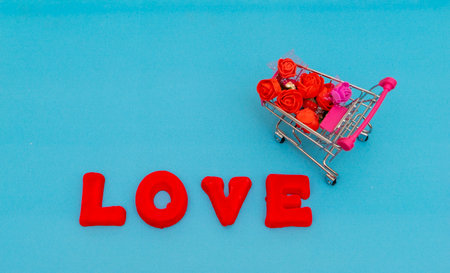 The word Love in red letters and a food cart with flowers on a blue background. Creative Valentine's Day mock up. Love flat lay with word.の写真素材