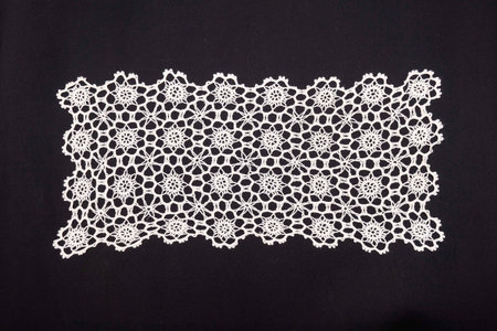 Vintage handmade white knitted napkin isolated on a black background.の写真素材