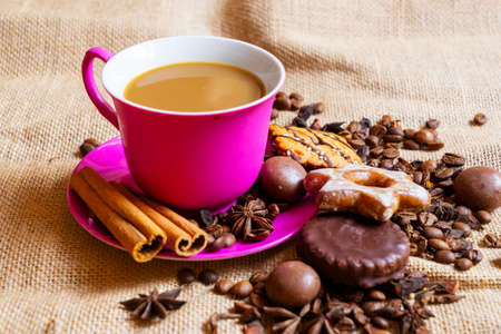 Red cup and saucer with coffee and coffee beans on a brown rag background.の写真素材