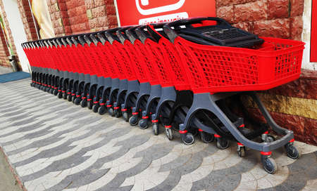 Row of red plastic shopping carts parking in the supermarket. Concept of shopping. Supermarket grocery push cart for shoppingの写真素材