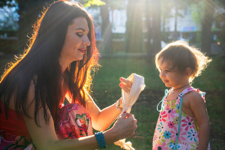 Happy mother and daughter in the park. Beauty nature scene with family outdoor lifestyle. Happy family resting together on the green grass, having fun outdoor. Happiness and harmony in family life.の写真素材