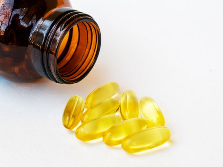 Pile of yellow fish oil capsules and pill glass bottle, fish oil contains omega-3 fatty acids, EPA and DHA, which reduce inflammation in the body, isolated on white background.の写真素材