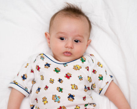 Cute baby lies on a white fluffy backgroundの写真素材