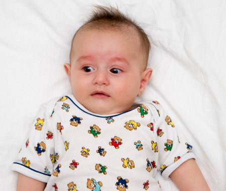 Cute baby lies on a white fluffy backgroundの写真素材