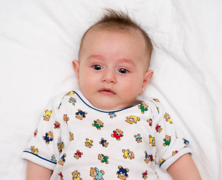 Cute baby lies on a white fluffy backgroundの写真素材