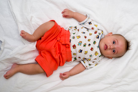 Cute baby lies on a white fluffy backgroundの写真素材