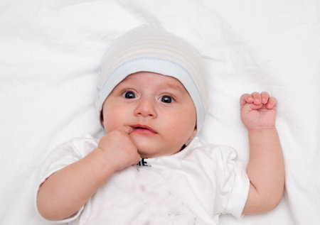 Cute baby lies on a white fluffy backgroundの写真素材