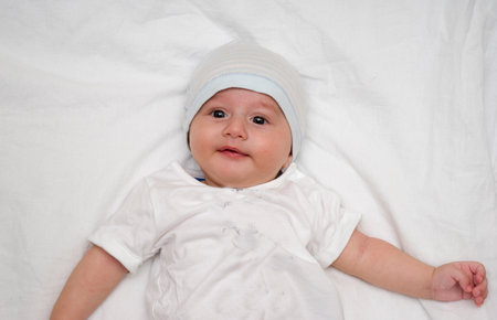 Cute baby lies on a white fluffy backgroundの写真素材