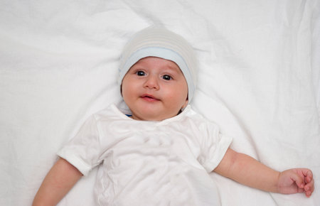 Cute baby lies on a white fluffy backgroundの写真素材