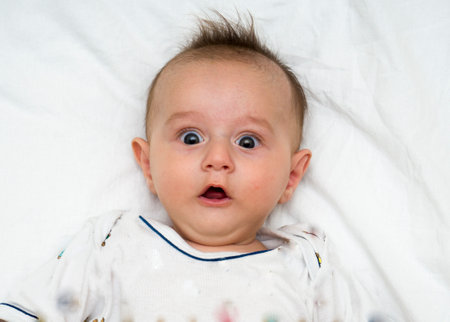 Cute baby lies on a white fluffy backgroundの写真素材