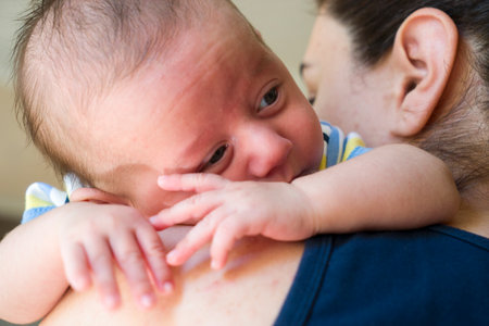 Baby little boy with blue eyes held in mother's arms for comfortの写真素材
