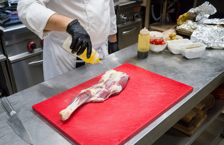 The chef also prepares lamb shank dishes. The process of cooking lamb shank male chef in a professional kitchen. Cooking meat in a Caucasian restaurant.の写真素材