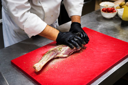 The chef also prepares lamb shank dishes. The process of cooking lamb shank male chef in a professional kitchen. Cooking meat in a Caucasian restaurant.の写真素材