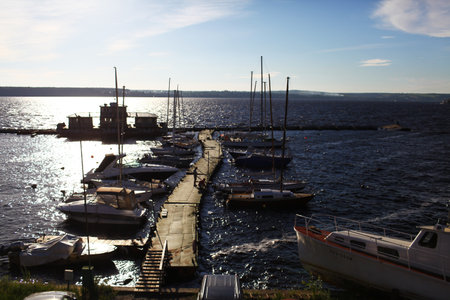 Sailing ships and yachts stand moored in port at the sunsetの写真素材