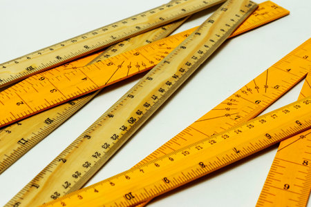 Close up of rulers from metric and imperial system on plywood room for copy white background.の写真素材