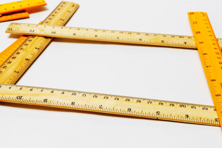 Close up of rulers from metric and imperial system on plywood room for copy white background.の写真素材