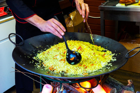 Cook prepares pilaf, a dish of rice and meat on a campfire in the kitchen of the restaurantの写真素材