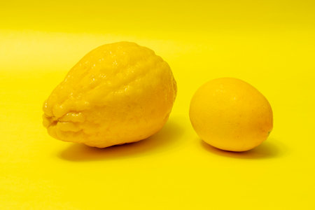 Juicy ripe lemons on a yellow background. A creative food concept. Tropical organic fruits, citrus fruits, vitamin C. Whole lemon. Summer minimalistic bright fruit background.の写真素材