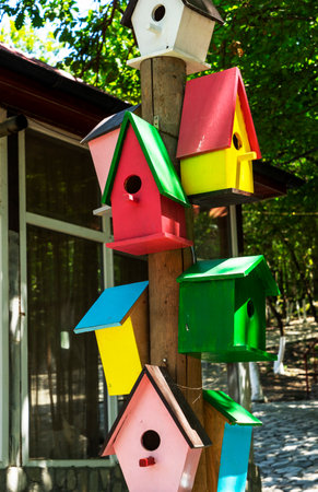 Colorful wooden birdhouses hang on wooden polesの写真素材