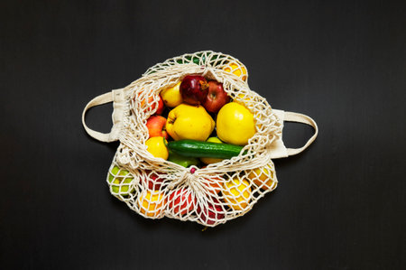 White string bag with different vegetables and fruits on a black background. top viewの写真素材
