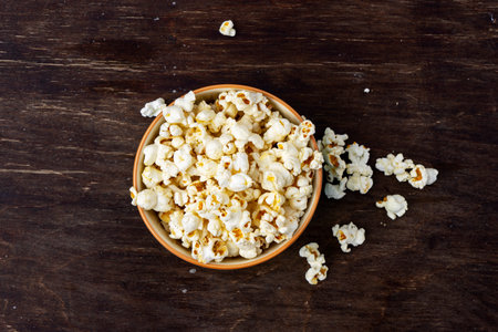 A plate of popcorn on a brown table, top viewの写真素材