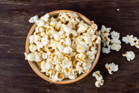 A plate of popcorn on a brown table, top viewの写真素材