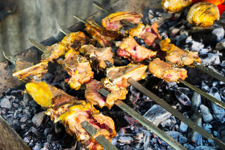 A lot of kebab skewers on the grill, on the coals close-up in the smoke.