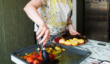 female lays fried vegetables on a plate,Grilled vegetables, roasted slices of potatoes, eggplants and zucchini, vegetarian and vegan dish, close upの写真素材